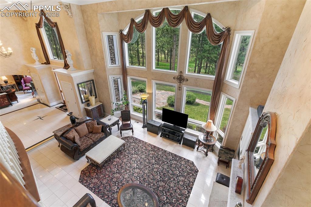 Image 9 of 50: Tiled living room with a towering ceiling, a chandelier, and a textured wal