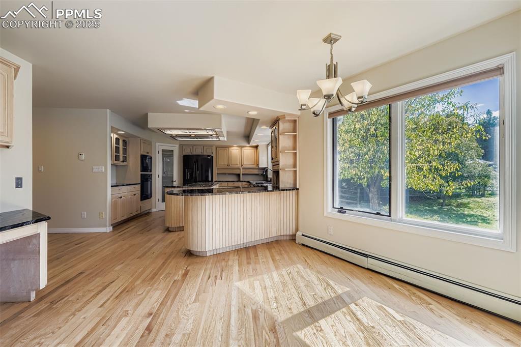 Image 14 of 35: Dining space with light wood finished floors, a chandelier, and a baseboard