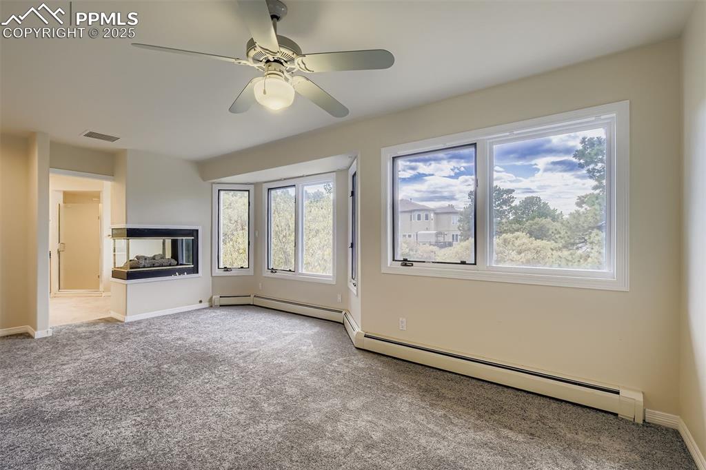 Image 19 of 35: Unfurnished living room featuring light carpet, a baseboard radiator, and c