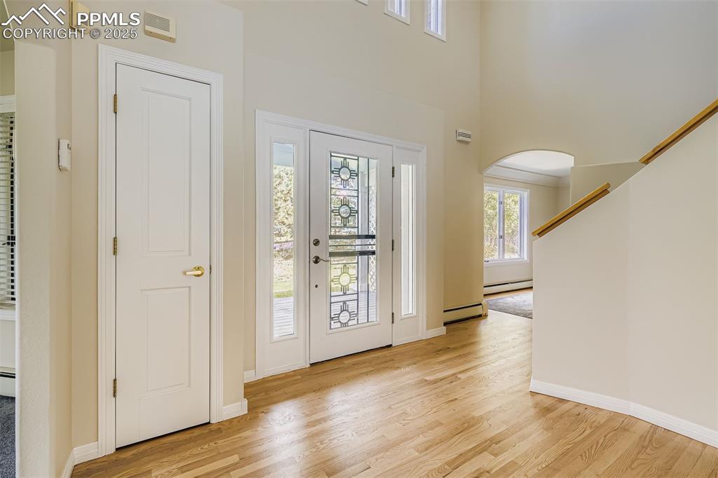 Image 2 of 35: Foyer featuring arched walkways, light wood-type flooring, baseboard heatin
