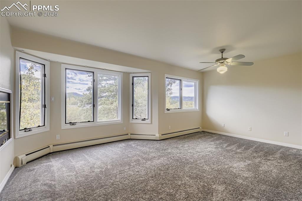 Image 20 of 35: Primary Bedroom featuring carpet floors, baseboard heating, gas fireplace a