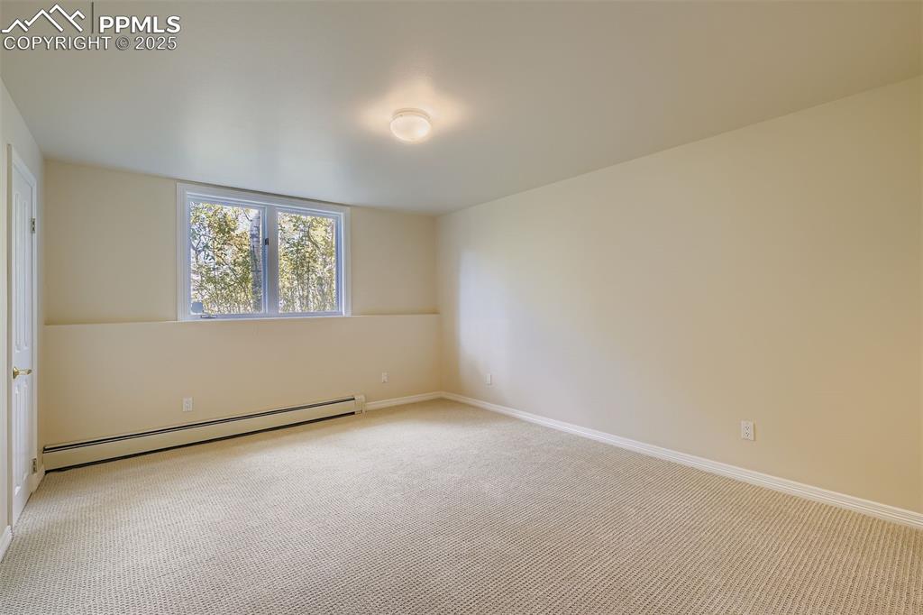 Image 31 of 35: Spare room featuring a baseboard radiator and carpet flooring