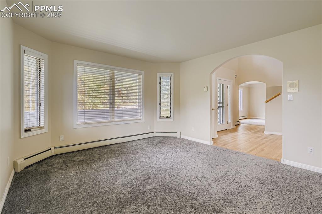 Image 9 of 35: Office featuring arched walkways, light carpet, and a baseboard heating uni