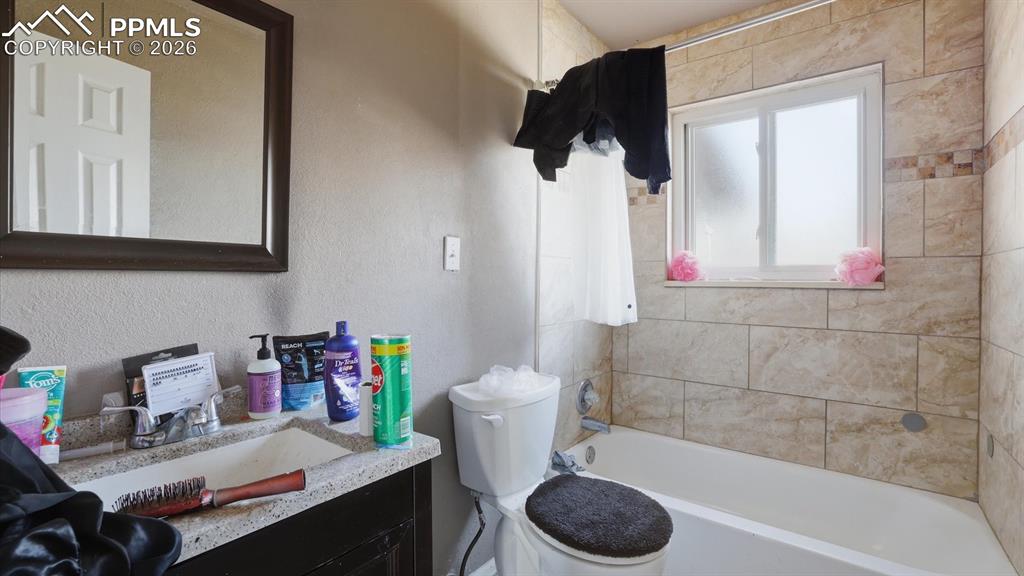 Image 16 of 30: Upper Level Full Bathroom with vanity, framed mirror, and tiled tub/shower.