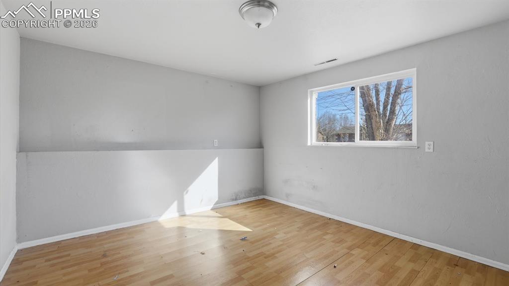 Image 18 of 30: Lower Level Bedroom #3 with wood laminate flooring and window.