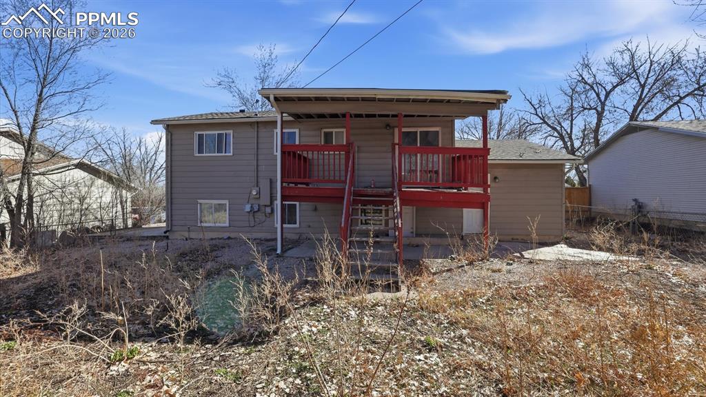 Image 25 of 30: Rear view of home with covered deck and concrete patio.