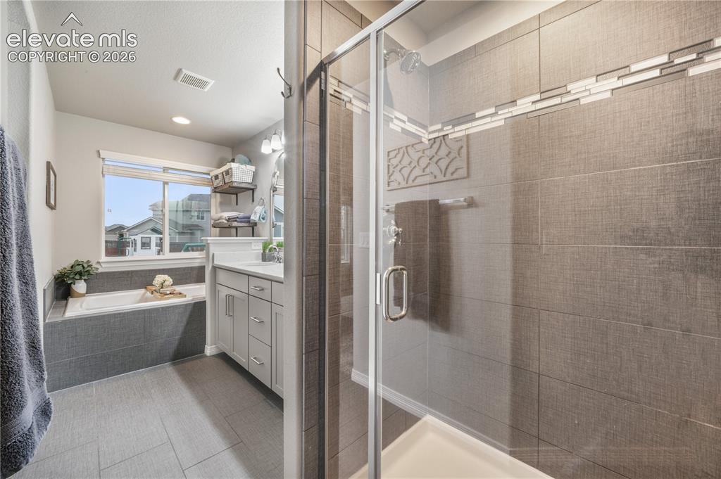 Image 19 of 50: Glass-enclosed shower with tiled walls and a decorative accent band
