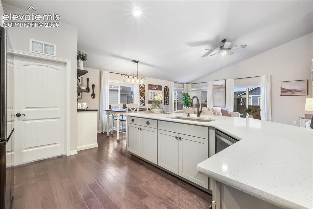 Image 2 of 50: Wood-finish flooring, vaulted ceiling, white cabinetry, integrated sink, an