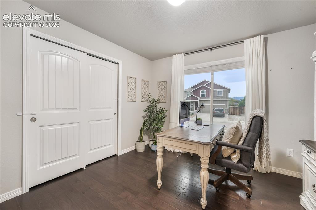 Image 21 of 50: Room with dark wood-finish flooring, light-colored walls, and a large windo