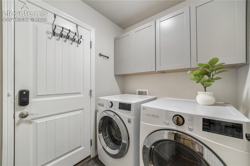 Image 23 of 50: White paneled door with smart lock, overhead cabinetry with light wood acce