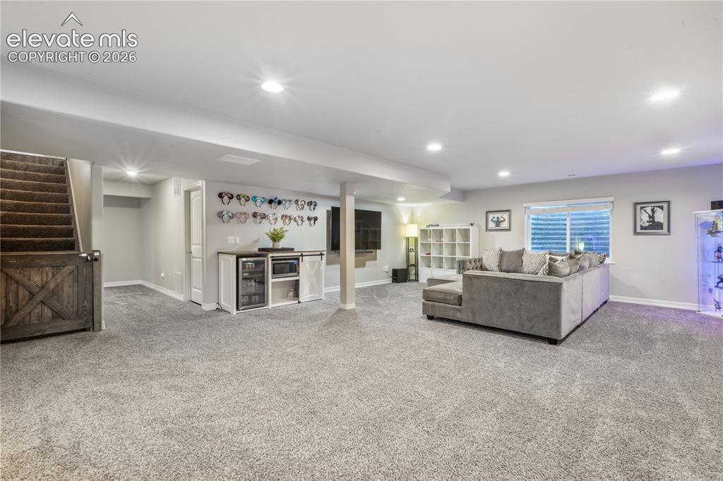 Image 25 of 50: Finished lower level featuring recessed lighting, a built-in wet bar, and c