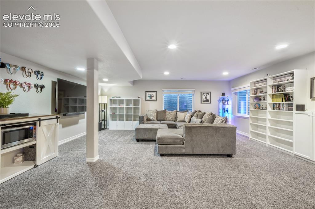 Image 26 of 50: Recessed lighting, wood-finish flooring, built-in shelving, and white baseb