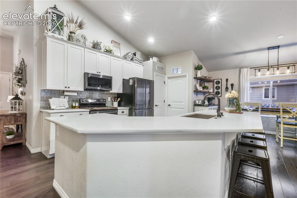 Image 3 of 50: Kitchen featuring white cabinetry, a large kitchen island with a built-in s