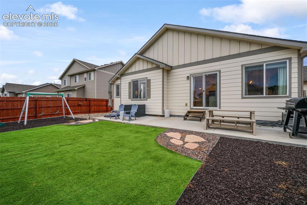 Image 39 of 50: Expansive artificial turf lawn with a stepping stone pathway and mulched la