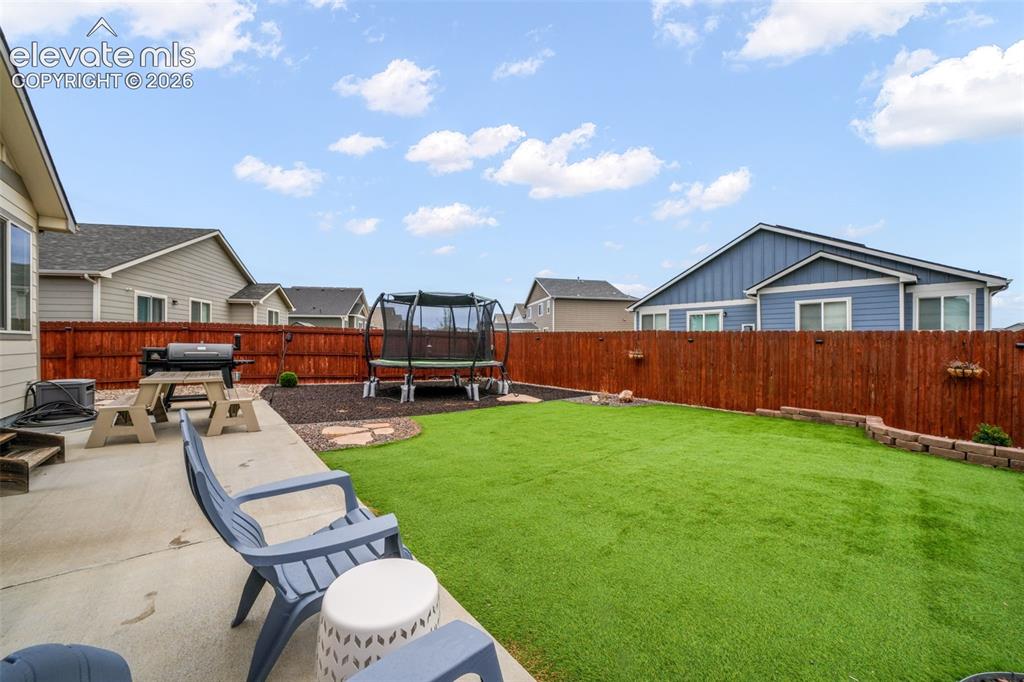 Image 40 of 50: Expansive backyard featuring a concrete patio, artificial turf lawn, and a 