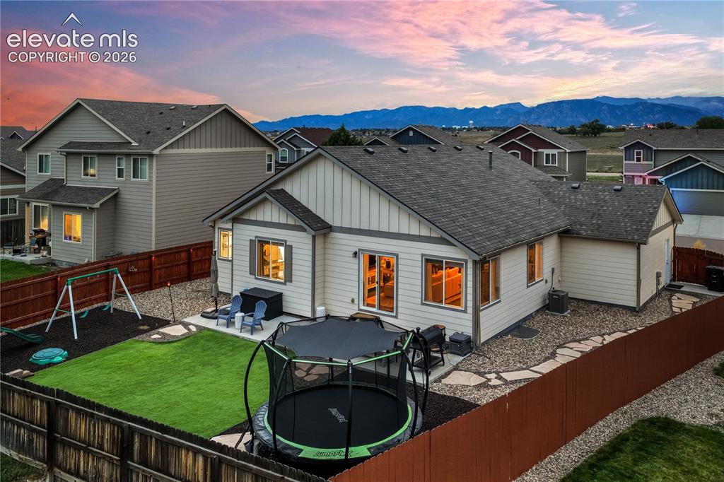 Image 41 of 50: Fully fenced backyard with a patio, artificial turf, and a gravel perimeter