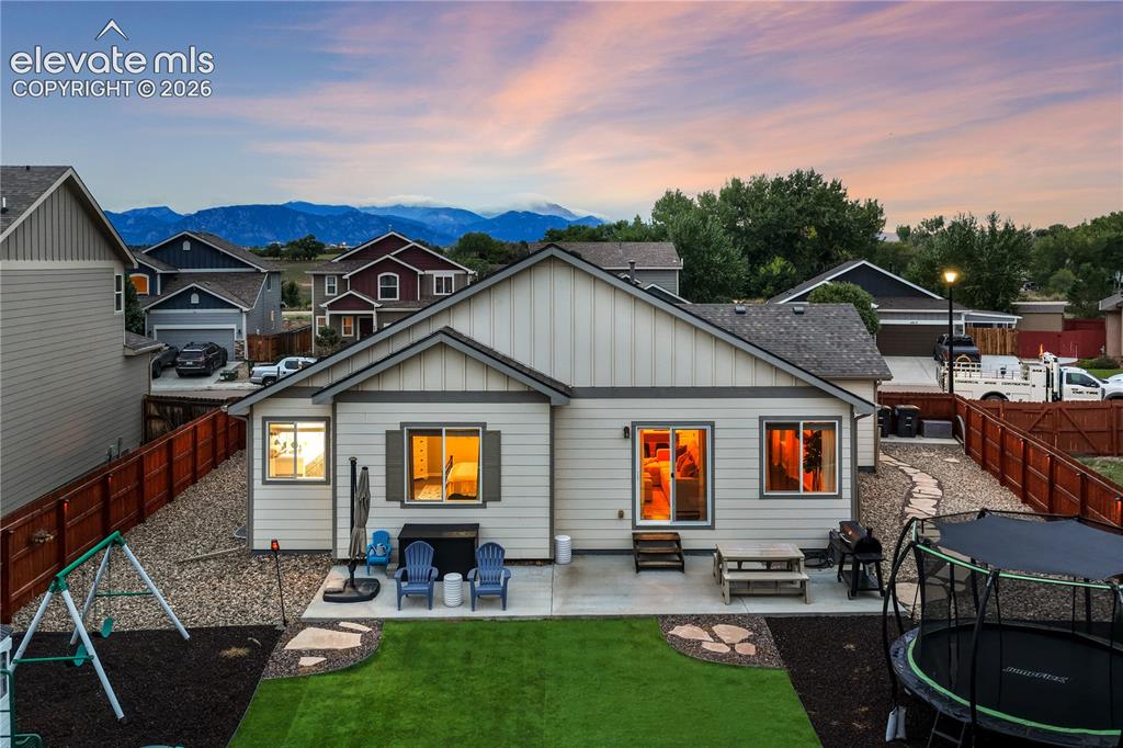 Image 42 of 50: Rear exterior with a concrete patio, artificial turf, and a wood privacy fe