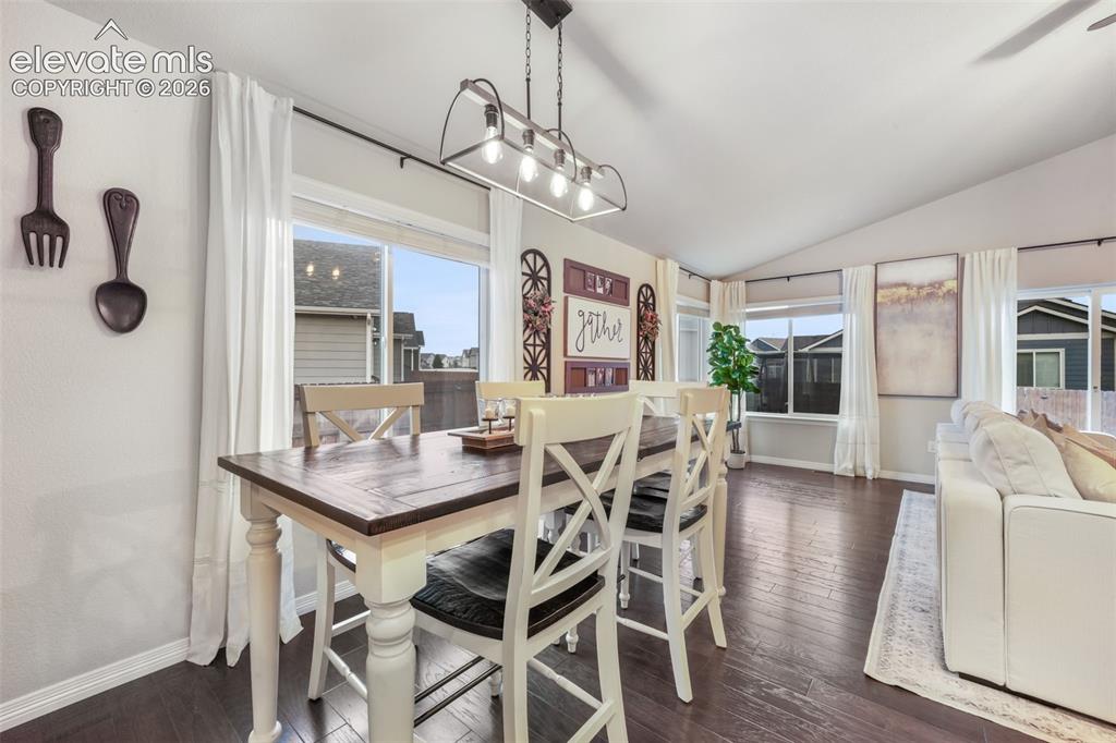 Image 7 of 50: Vaulted ceiling with a linear chandelier, large windows with curtain rods, 