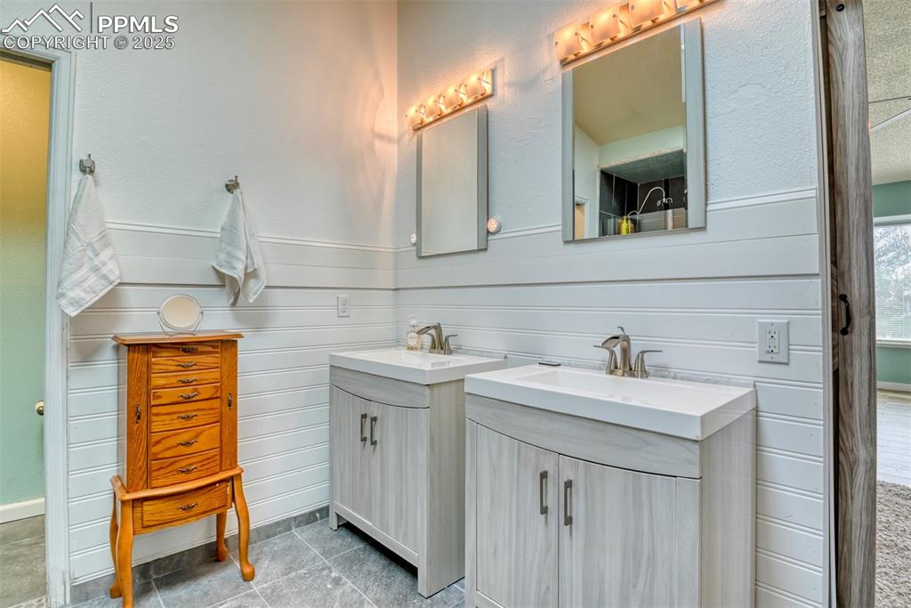 Image 18 of 45: Full bathroom featuring a wainscoted wall, two vanities, wooden walls, and 