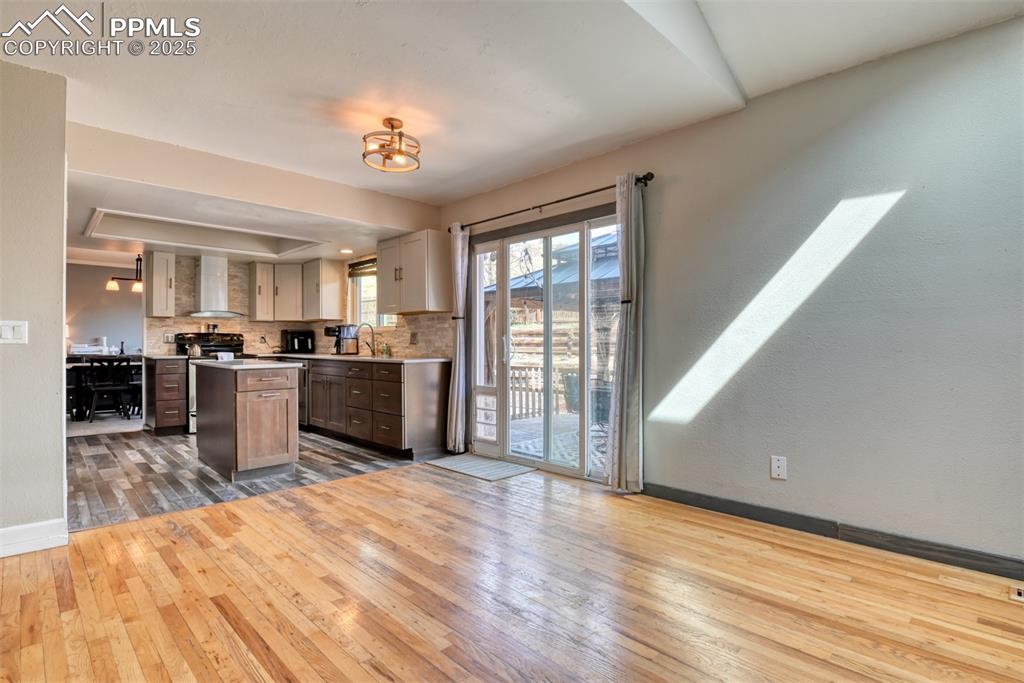 Image 3 of 45: Kitchen featuring wall chimney range hood, decorative backsplash, light cou