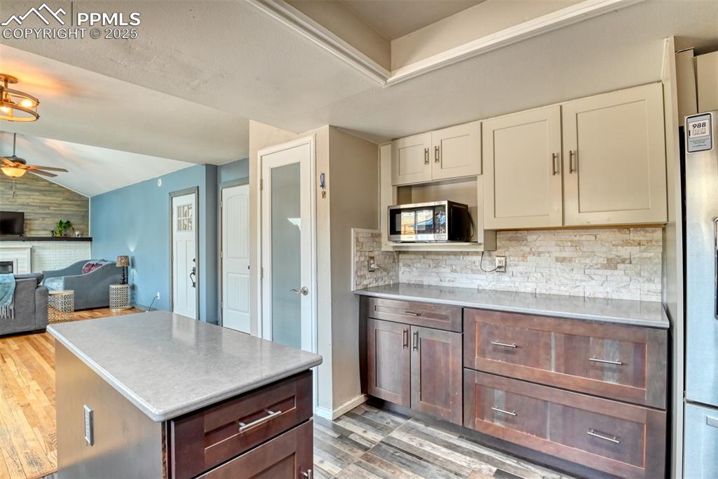 Image 7 of 45: Kitchen with light countertops, vaulted ceiling, a ceiling fan, stainless s
