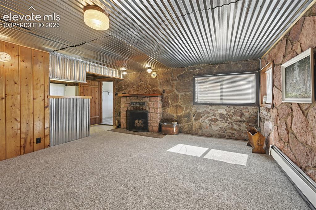 Image 25 of 45: Garden-level family room in the basement with fireplace and stone walls tha