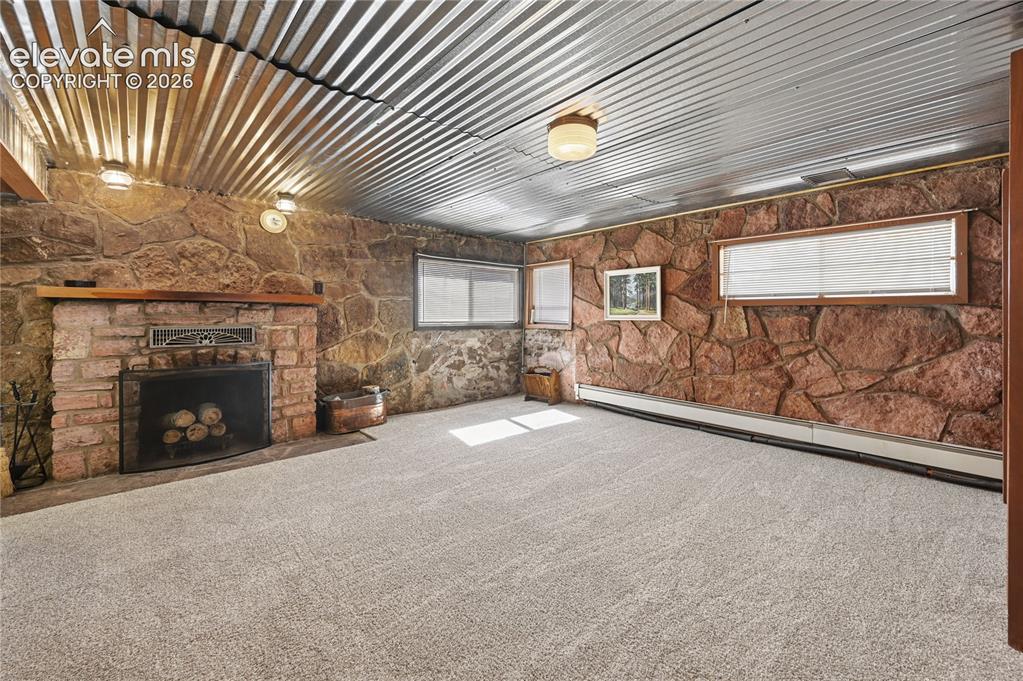 Image 26 of 45: Garden-level family room in the basement with fireplace and stone walls tha