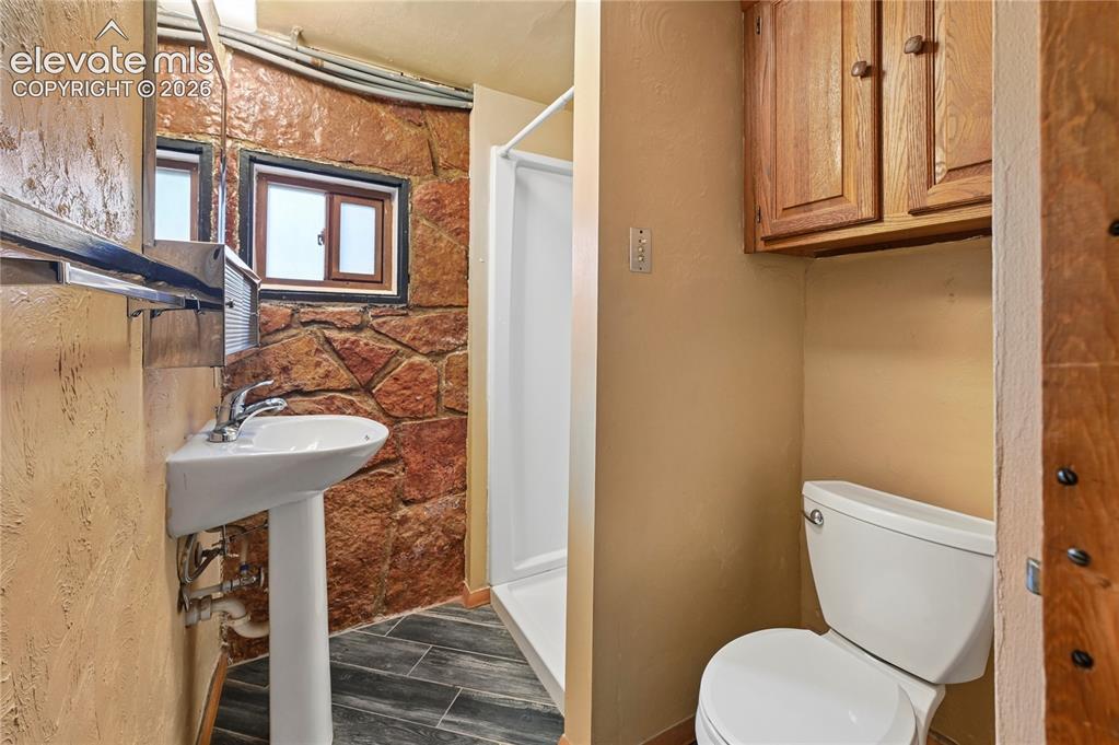 Image 31 of 45: 3/4 bathroom in the basement with the stone walls that lend a historic moun