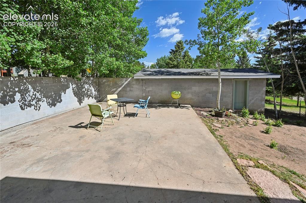 Image 35 of 45: The garage wall bounds one side of the paved patio & dog run area.