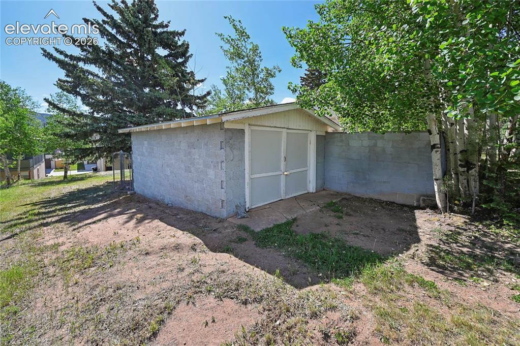 Image 4 of 45: One-car cement block garage that joins one of the patio patio walls