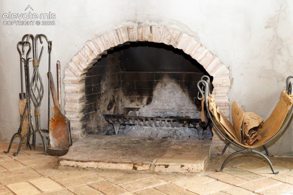 Image 10 of 50: Masonry fireplace with a brick arch and hearth