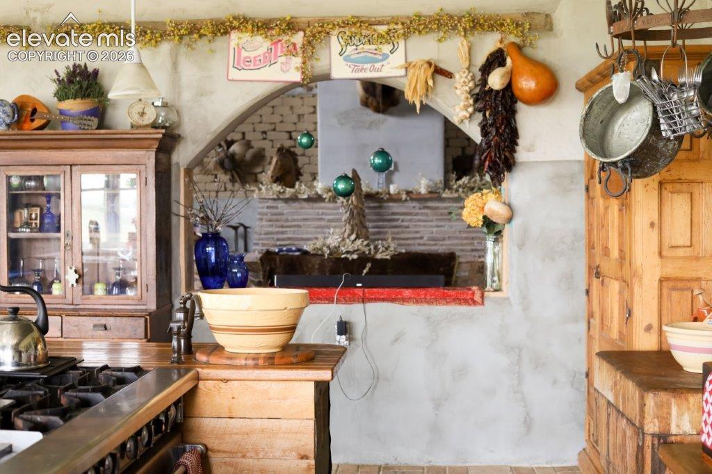 Image 13 of 50: Rustic kitchen featuring a gas range, wooden cabinetry with glass inserts,