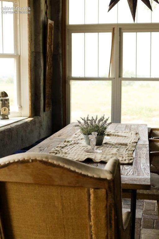 Image 14 of 50: Sunlit dining space featuring a distressed wood table and white-framed case