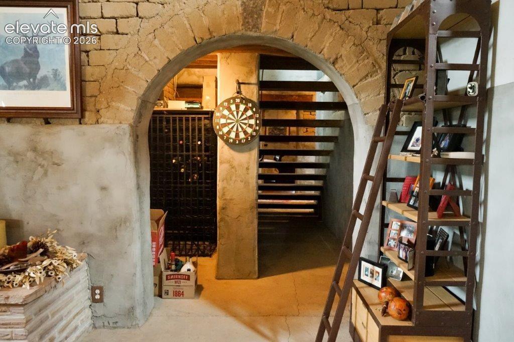 Image 17 of 50: Stone archway entrance featuring a visible wine rack behind a metal gate, o