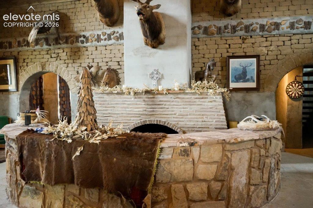 Image 18 of 50: Living Room/Great Room with adobe brink wall, brick fireplace with sunken s