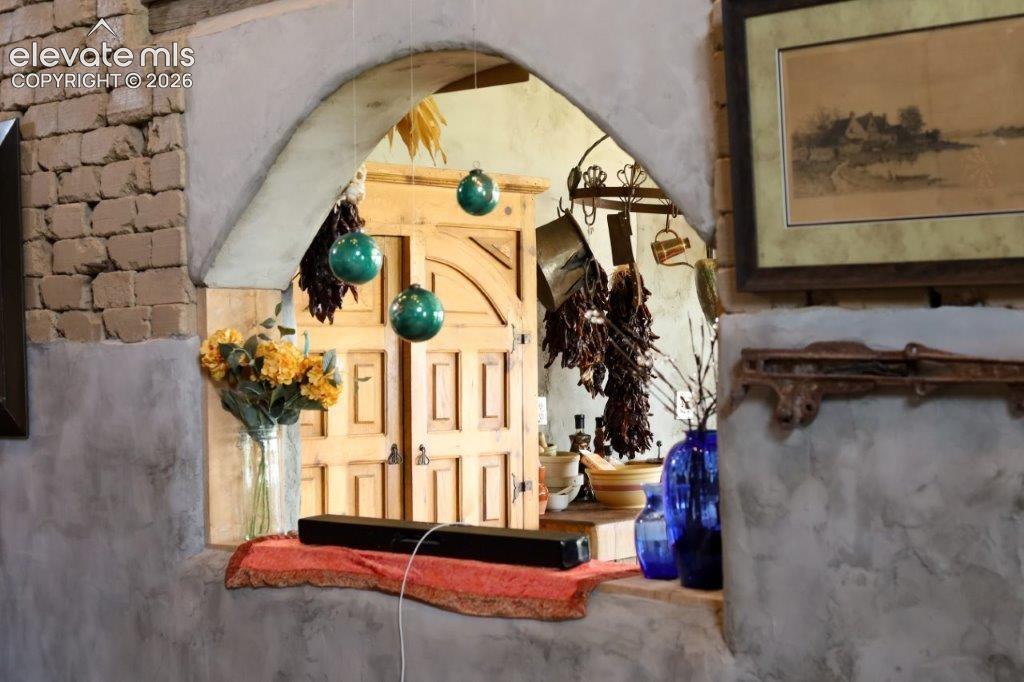 Image 22 of 50: Arched interior window with a deep sill, featuring textured adobe walls and