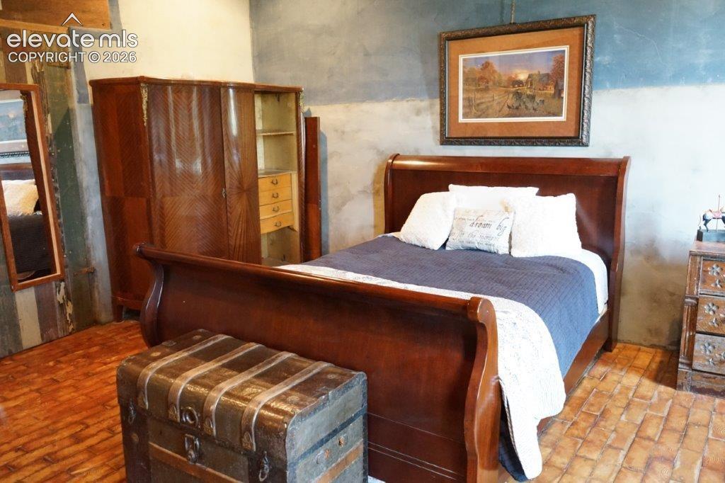 Image 28 of 50: Bedroom featuring brick-patterned flooring, a slate-toned accent wall, and