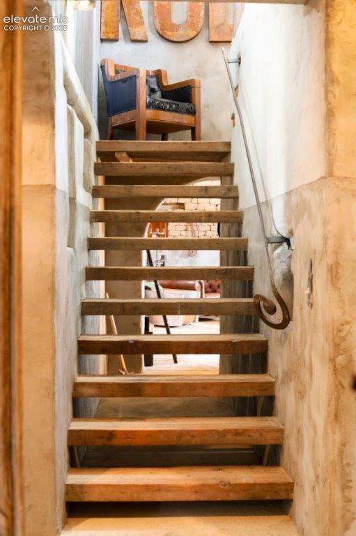 Image 38 of 50: Open-tread staircase featuring wood-finish steps and a wrought-iron handrai