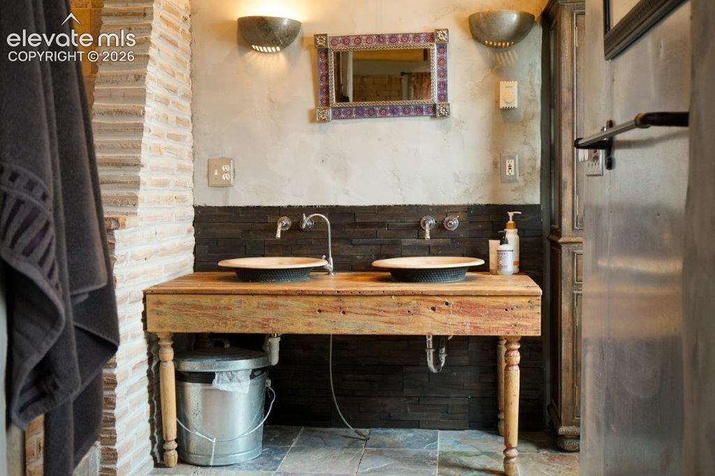 Image 44 of 50: Dual vessel sinks set on a rustic wood-finish vanity, complemented by a mos