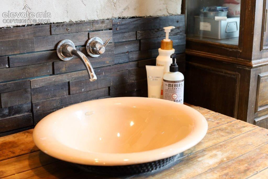Image 49 of 50: Vessel sink and wall-mounted faucet with a wood-finish countertop and dark