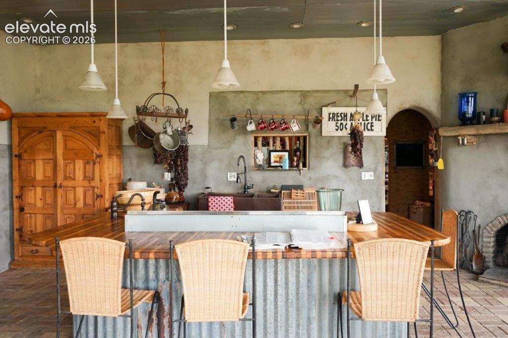 Image 8 of 50: Rustic-inspired kitchen area featuring a corrugated metal island with a woo