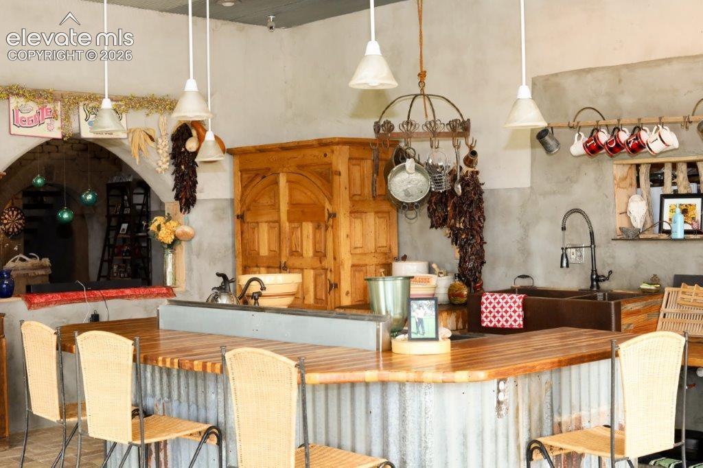 Image 9 of 50: Kitchen featuring a corrugated metal breakfast bar with a wood-finish count