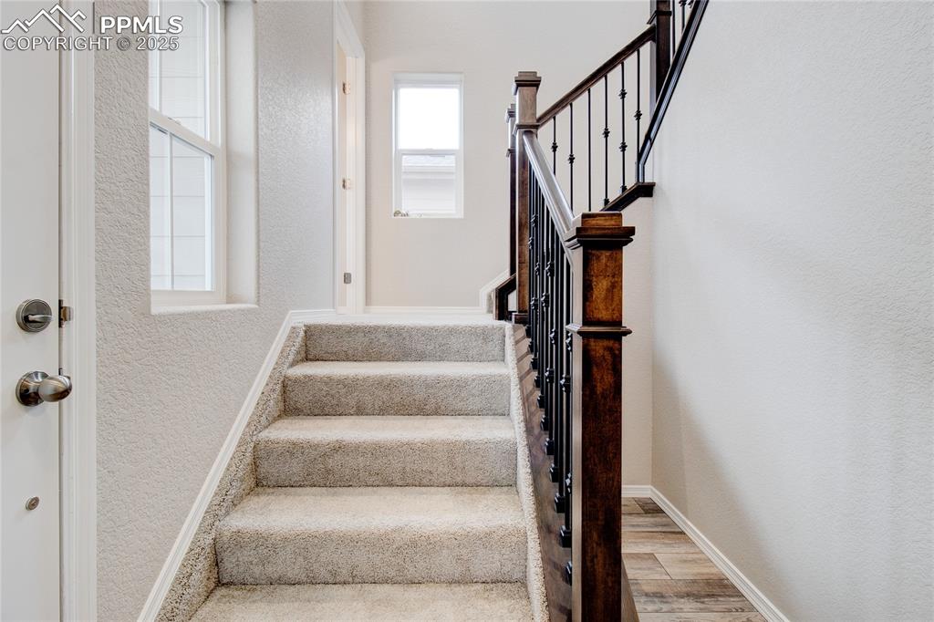 Image 11 of 24: Stairway featuring a textured wall and wood finished floors