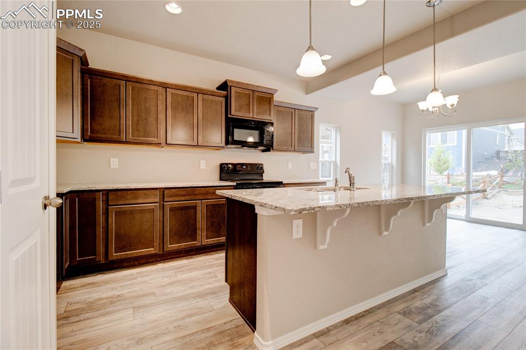 Image 2 of 24: Kitchen with light stone countertops, a breakfast bar, recessed lighting, b