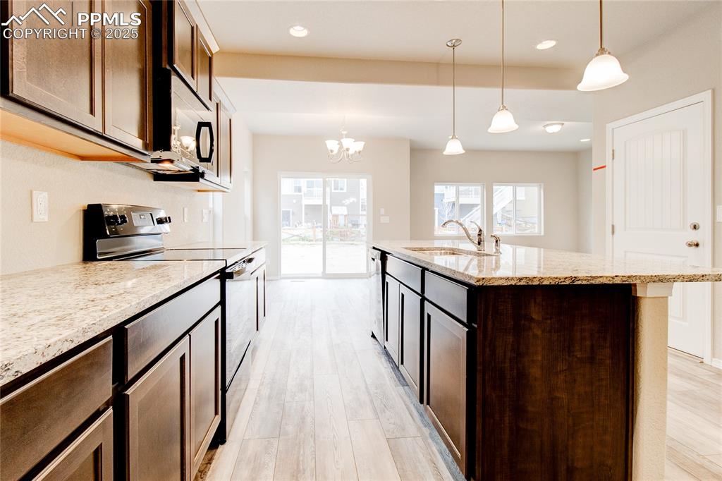 Image 5 of 24: Kitchen with stainless steel appliances, decorative light fixtures, light s