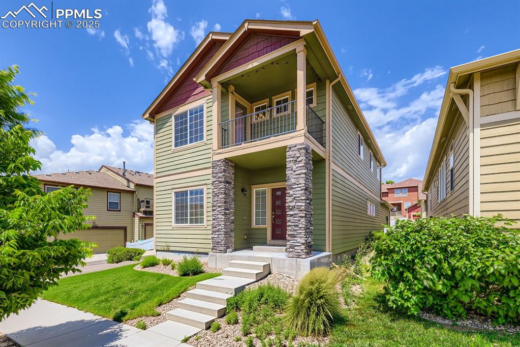 Caption: Craftsman house featuring a balcony, a front lawn, and stone siding