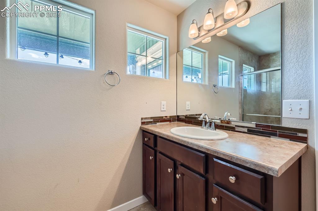 Image 22 of 31: Bathroom with a textured wall, vanity, and a shower stall