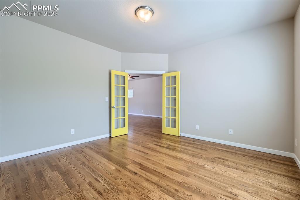 Image 8 of 31: Empty room with french doors and wood finished floors