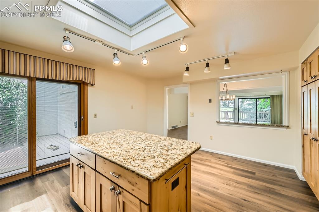 Image 12 of 29: Kitchen with light wood-type flooring, a kitchen island, a chandelier, and