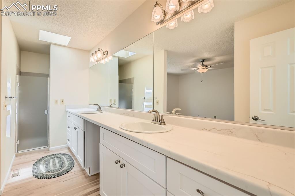 Image 19 of 29: Full bath featuring a textured ceiling, double vanity, wood finished floors